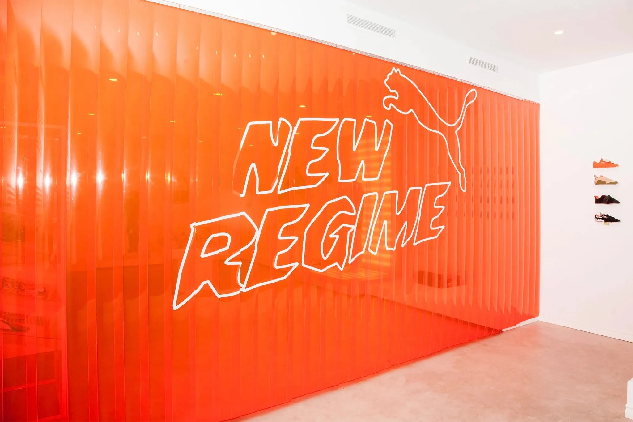Grand mur orange portant les signatures New Regime et PUMA dans l’espace de présentation